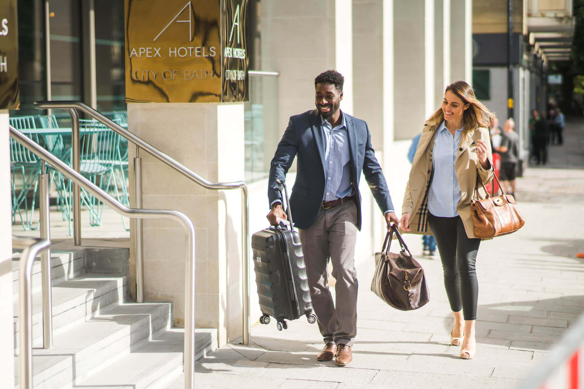 Staff member helping guest into hotel with her bags