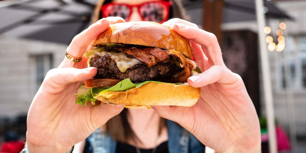 Hands holding a burger at BRGR+BUBBLES