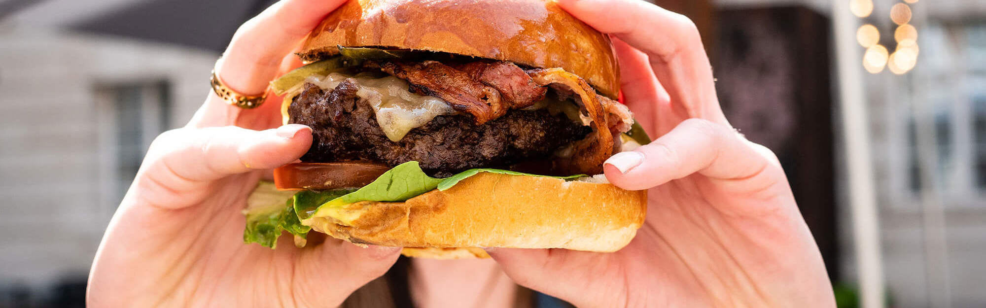 Hands holding a burger at BRGR+BUBBLES