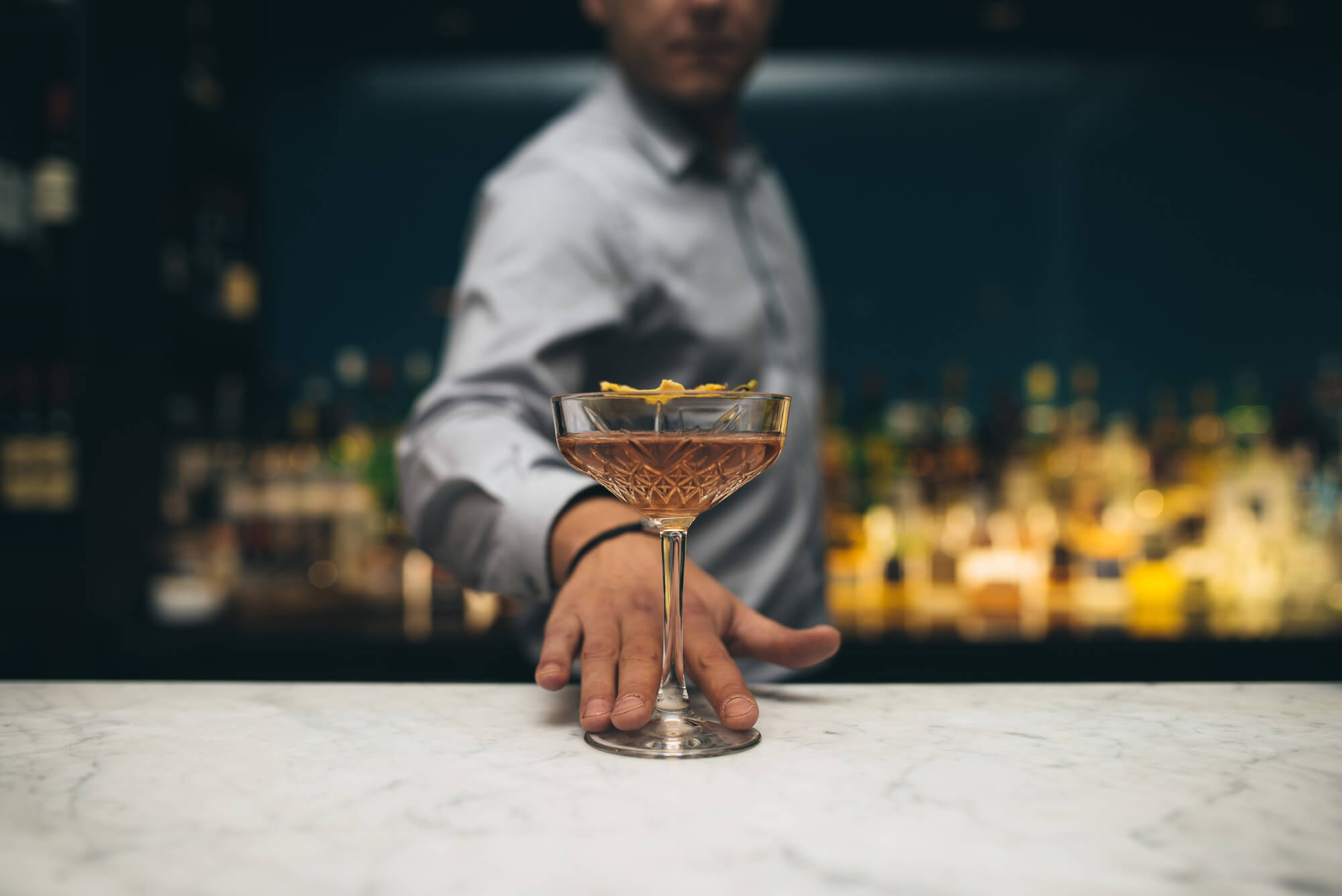 Bartender sliding cocktail across the bar