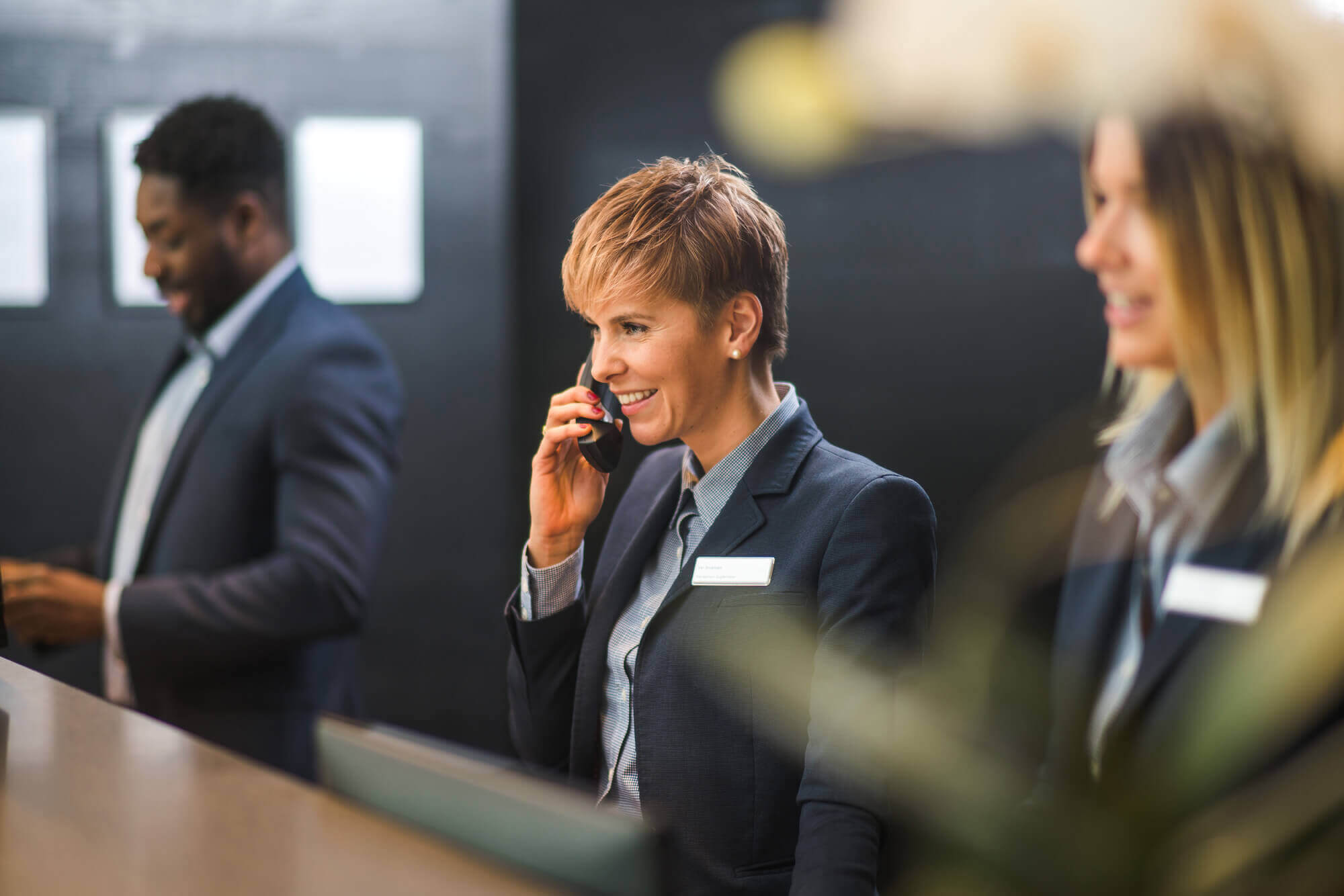 Three receptionists with female employee in the middle on the phone