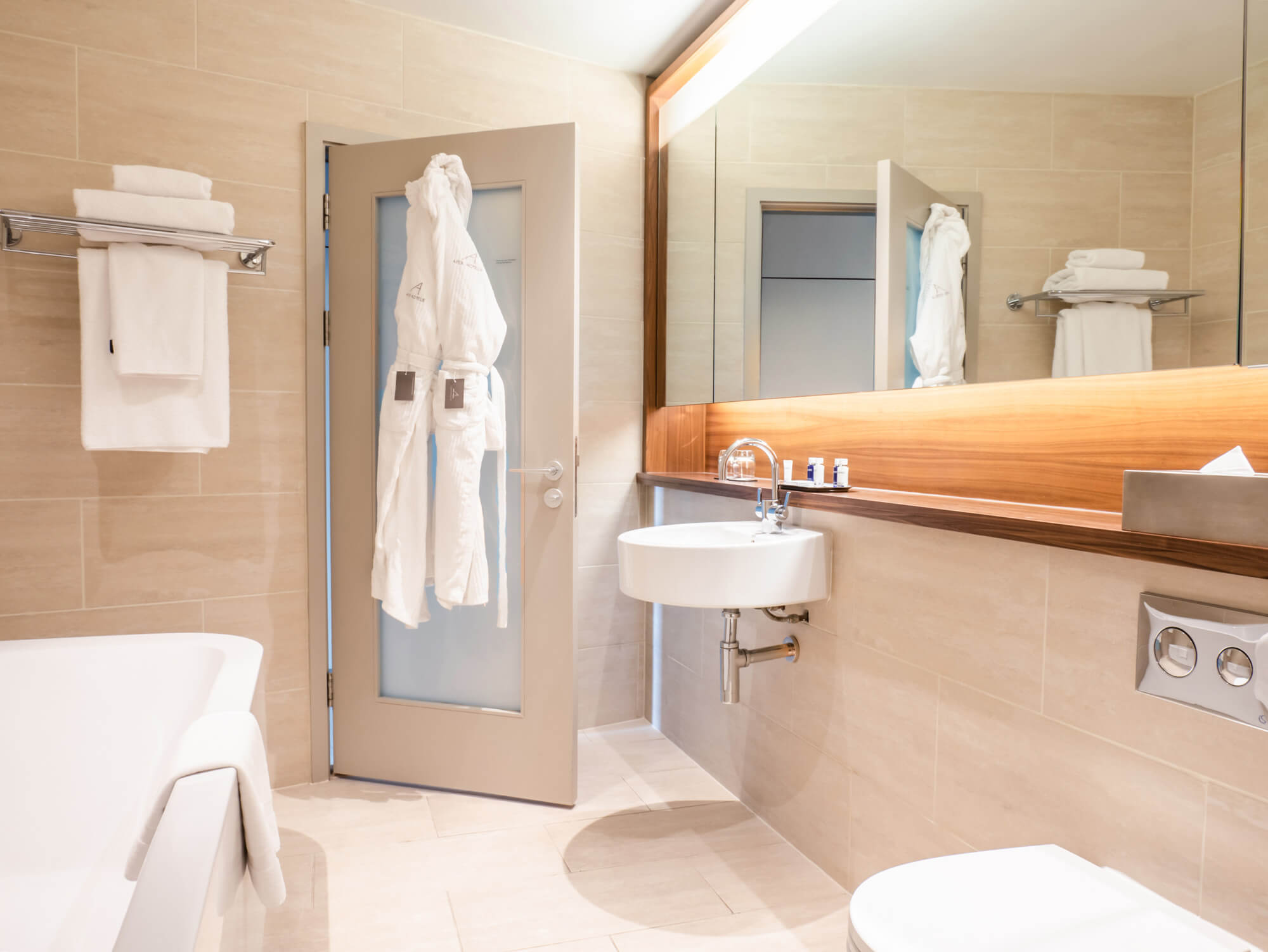 Superior Room bathroom with bath and robes hanging on the back of door at Apex Waterloo Place Hotel