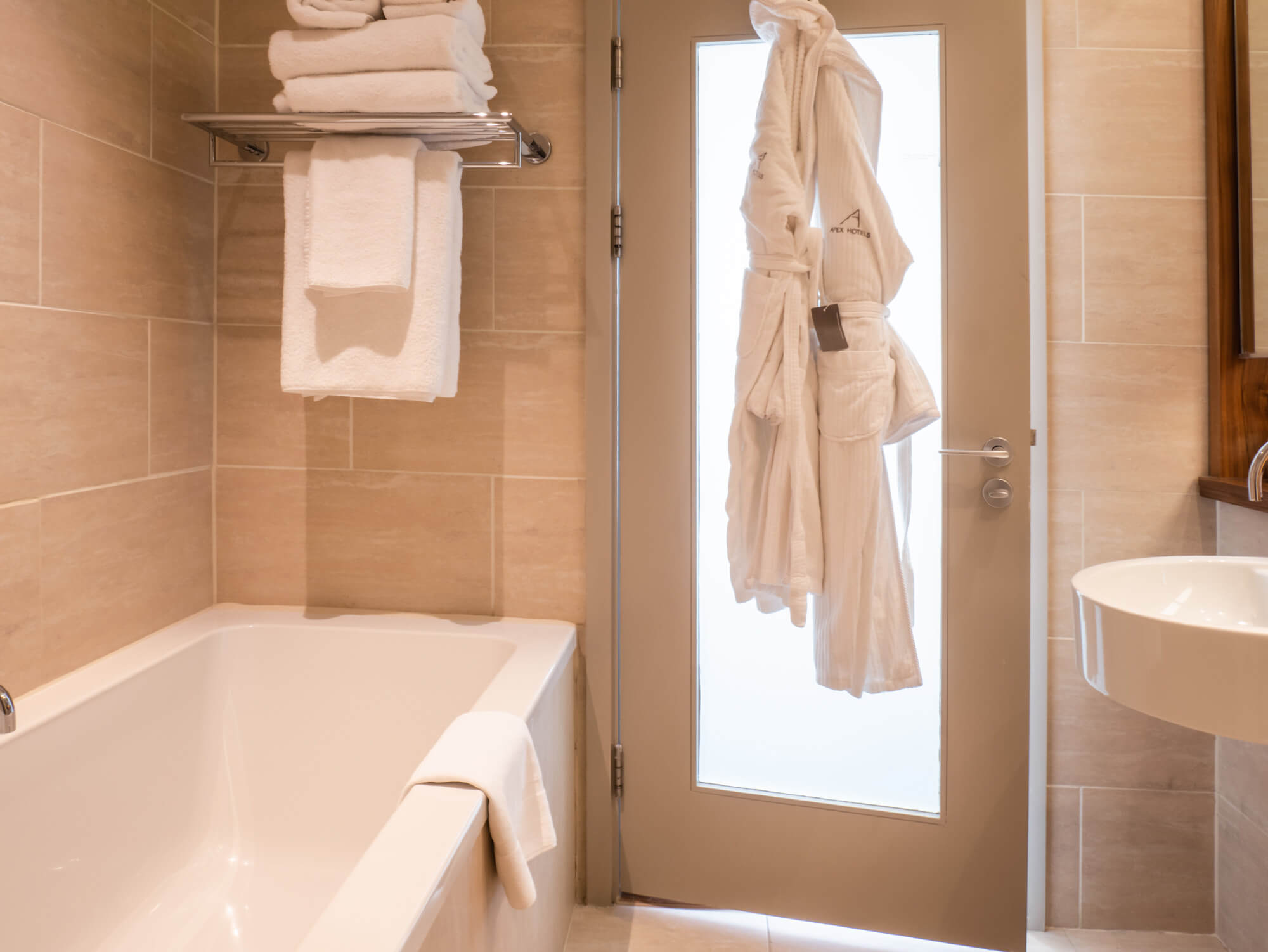 Family Room bathroom with bath and robes hanging on door at Apex Waterloo Place Hotel