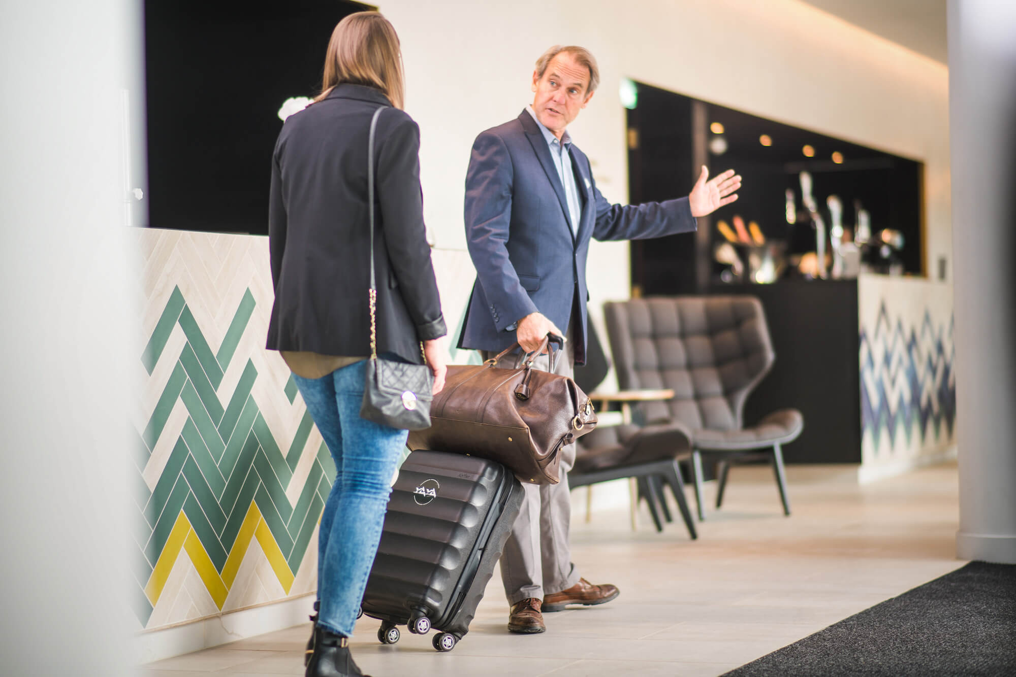 Male employee helping female guest with her bag in hotel